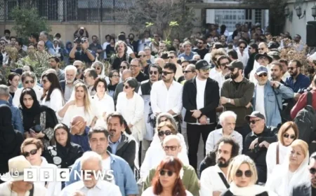 Pallbearers in White Carry Nasser Taghvai’s Coffin