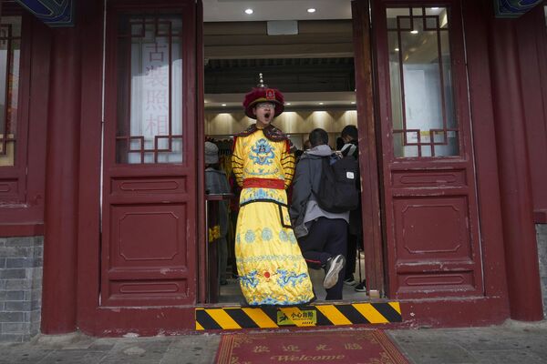 صاحب متجر للهدايا التذكارية يرتدي زيًا عتيقًا بالقرب من سور الصين العظيم في ضواحي بكين - البلد عربي